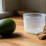 Avocat posé à côté d’objets de cuisine servant à estimer son poids sans balance.