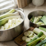 Poireaux présentés en différentes découpes, avec des rondelles, des lamelles et des tronçons prêts à cuire dans une cuisine lumineuse.
